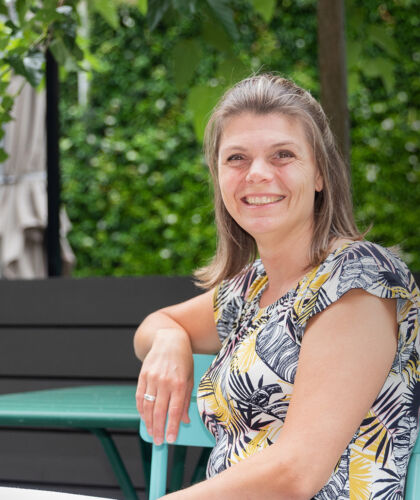 Portret medewerker in binnentuin met een boom op de achtergrond